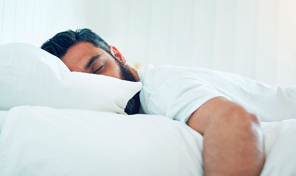 Hombre dormido en la cama. Bruxismo. Rechinar dientes al dormir.